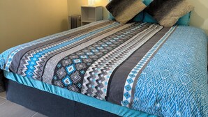 A bed with a patterned bedspread, two pillows, a bedside lamp, and a radiator. - Brandnew bedroom in a beautiful suburb  (Saint Albans)