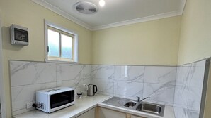 A compact kitchen with a microwave, sink, and window. - Brandnew bedroom in a beautiful suburb  (Saint Albans)