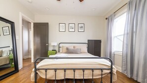 Een slaapkamer met een metalen bedframe, een nachtkastje met een lamp en een garderobe.