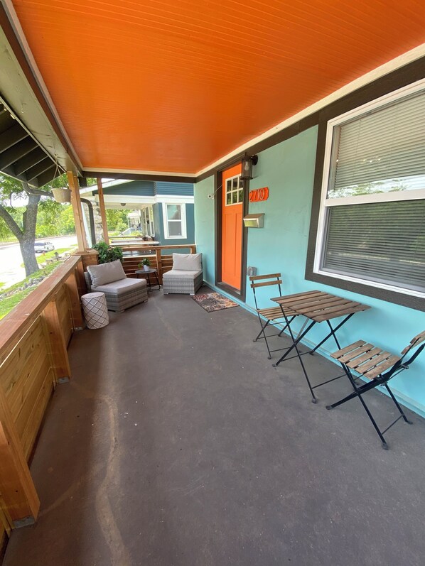A covered outdoor seating area with wooden furniture and a view of the street.