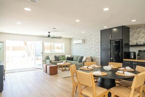 A modern kitchen with a dining area, a sofa, and a ceiling fan.