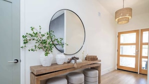 A hallway with a wooden console table, a large mirror, and a potted plant.