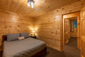 Un dormitorio con paneles de madera, una cama, mesitas de noche y una lámpara de noche.