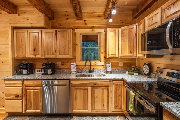 A wooden cabin kitchen with granite countertops, stainless steel appliances, and wooden cabinets.