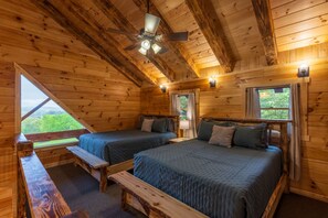 Eine Hütte mit zwei Betten, einem Deckenventilator und einem Fenster mit Blick auf Grünflächen.