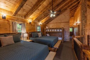 A log cabin room with two beds, a ceiling fan, and wooden walls.