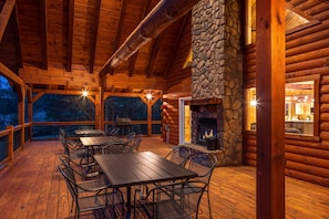 Una terraza de madera con mobiliario exterior y una chimenea de piedra.