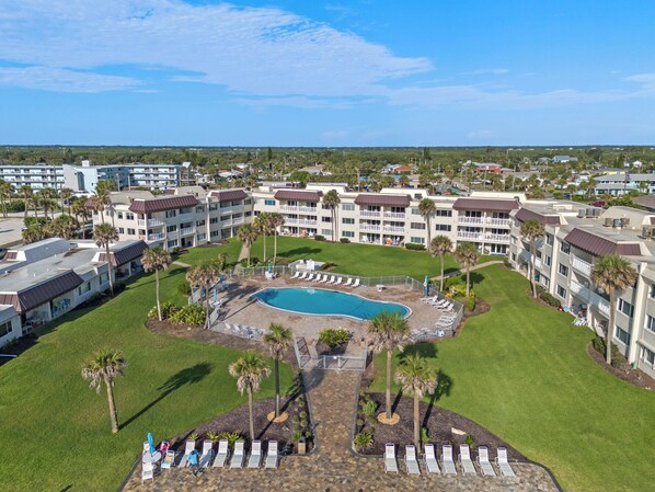 A resort with a central pool, multiple balconies, and a well-maintained lawn.