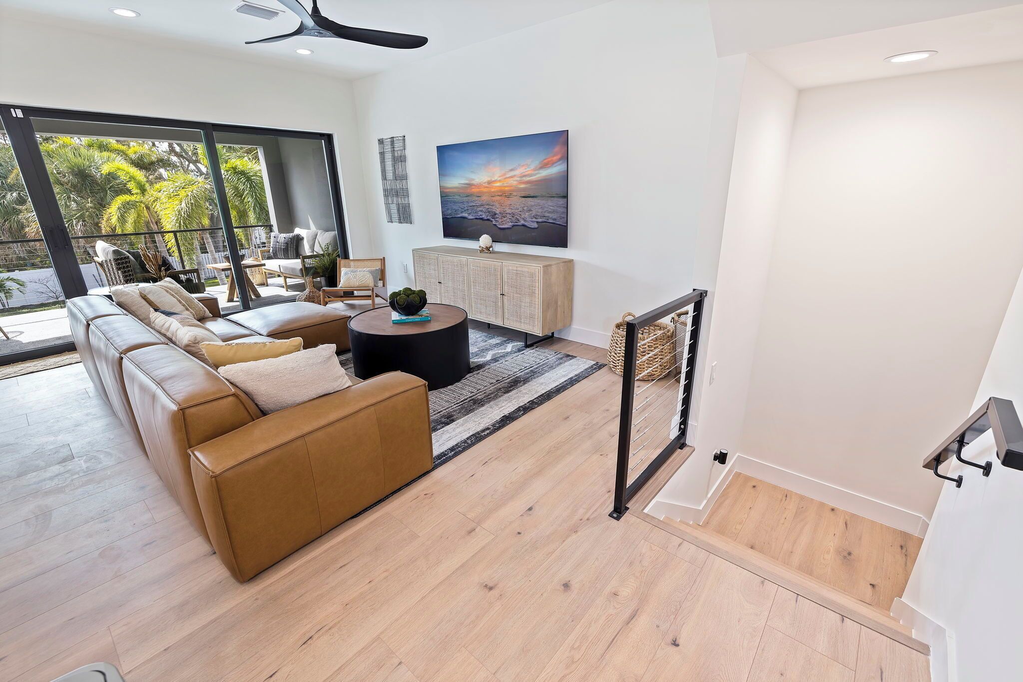 A modern living room with a large sofa, a coffee table, and a view of the outdoors.