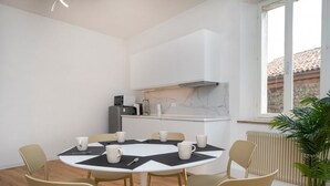 A modern kitchen with white cabinets, a black countertop, and a window with a view of a building. - GuestHost - Cividale Medieval Town Apartment (Cividale del Friuli)
