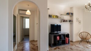 A modern living room with a TV, bookshelves, a chair, and a marble floor. - GuestHost - Splendid penthouse of 65 sqm located on the sixth floor of a residential building of the 70s with a wonderful terrace that offers views of the sea and the greenery. The apt. is located in via Lamarmora, a residential street above the famous t (Sanremo)