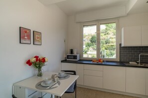 A kitchen with a dining table, a microwave, and a window with a view of greenery.