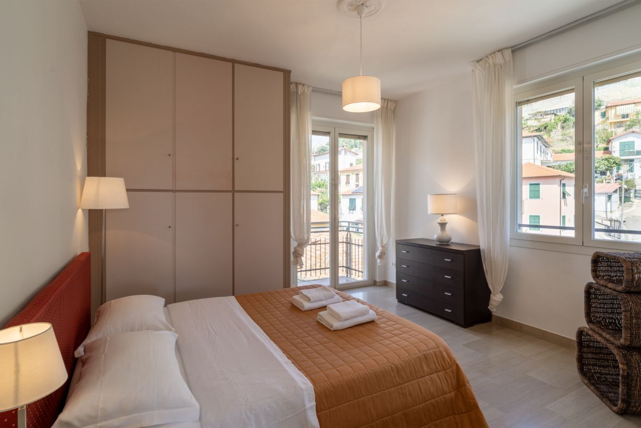 A hotel room with a bed, a dresser, a chair, and a view of the outside.
