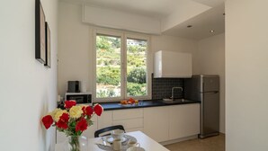 A modern kitchen with white cabinets, a stainless steel refrigerator, and a dining area with a table set for two. - GuestHost - Splendid penthouse of 65 sqm located on the sixth floor of a residential building of the 70s with a wonderful terrace that offers views of the sea and the greenery. The apt. is located in via Lamarmora, a residential street above the famous t (Sanremo)