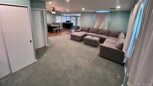 Ein geräumiges Wohnzimmer mit einer Eckcouch, Hockern und einem Essbereich mit Tisch und Stühlen.