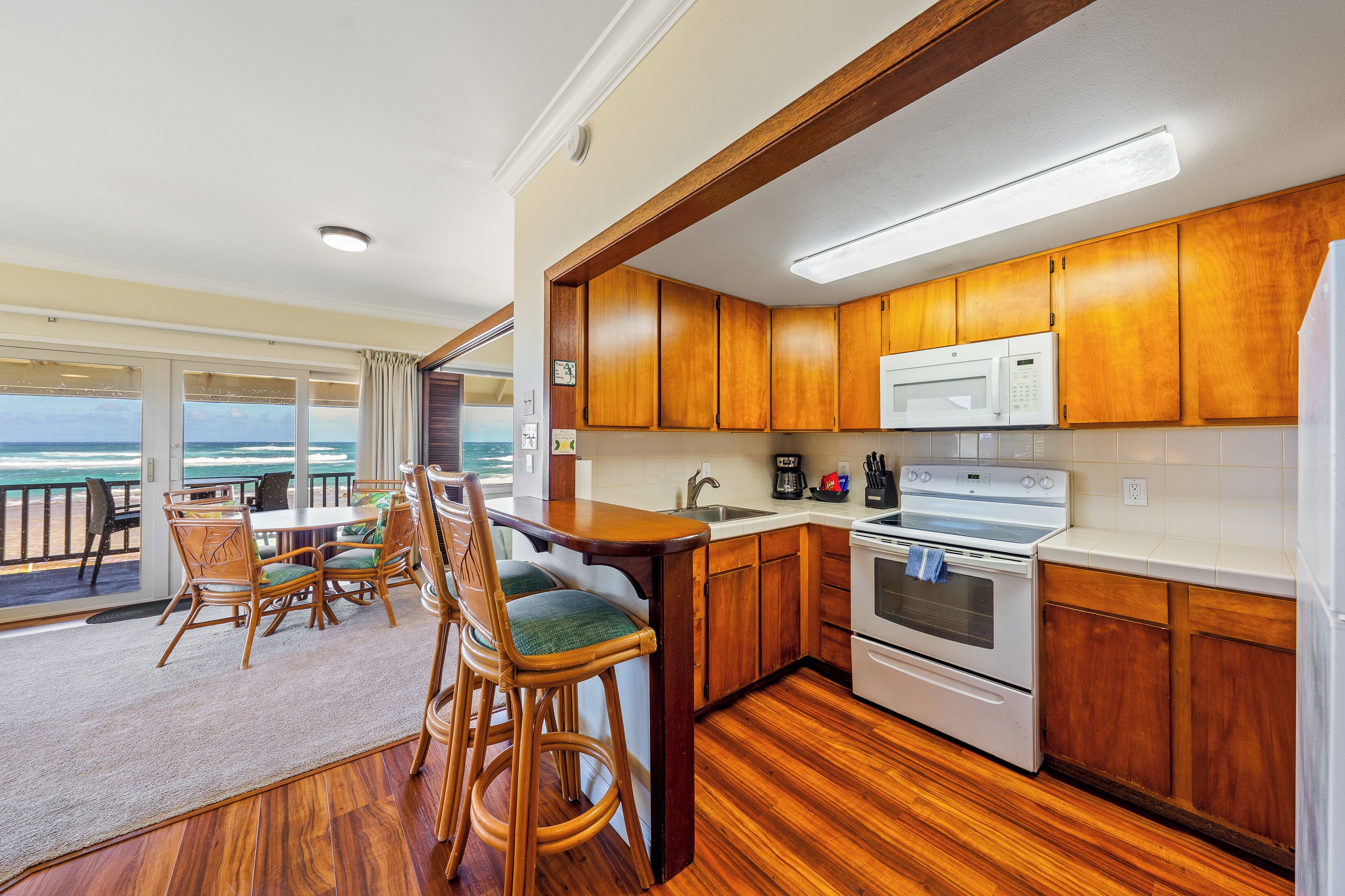 A kitchen with wooden cabinets, a microwave, and an oven. There is a dining area with chairs and a table.