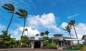 A building with a sign reading "Opakapaka" and a logo, surrounded by palm trees and greenery. - Hanalei Colony Resort F3 (Hanalei)