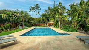 A rectangular swimming pool with a tiled deck, surrounded by palm trees and lush greenery. - Hanalei Colony Resort F3 (Hanalei)
