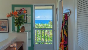 A door with a view of the ocean, a vase with flowers, and a colorful towel hanging on a hook. - Hanalei Bay Villa 26 (Princeville)