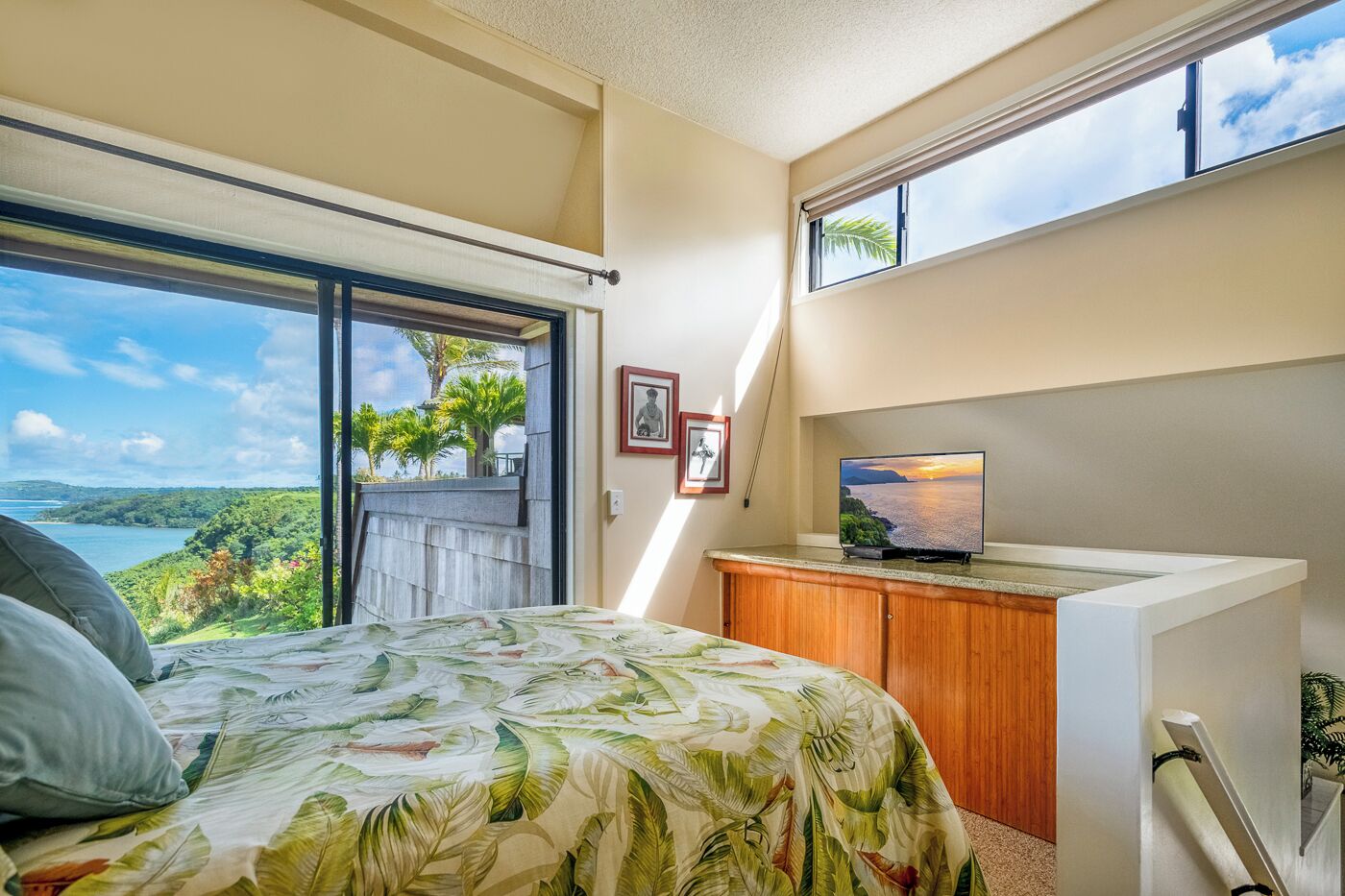 A bedroom with a bed, a television, a window, and a view of a landscape.