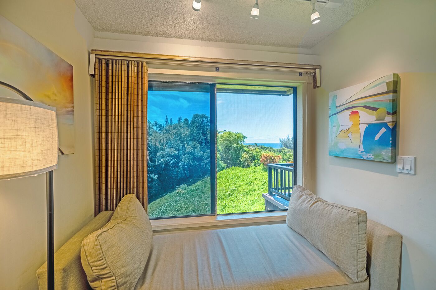 Une chambre avec un lit, une fenêtre donnant sur un paysage verdoyant et un tableau accroché au mur.