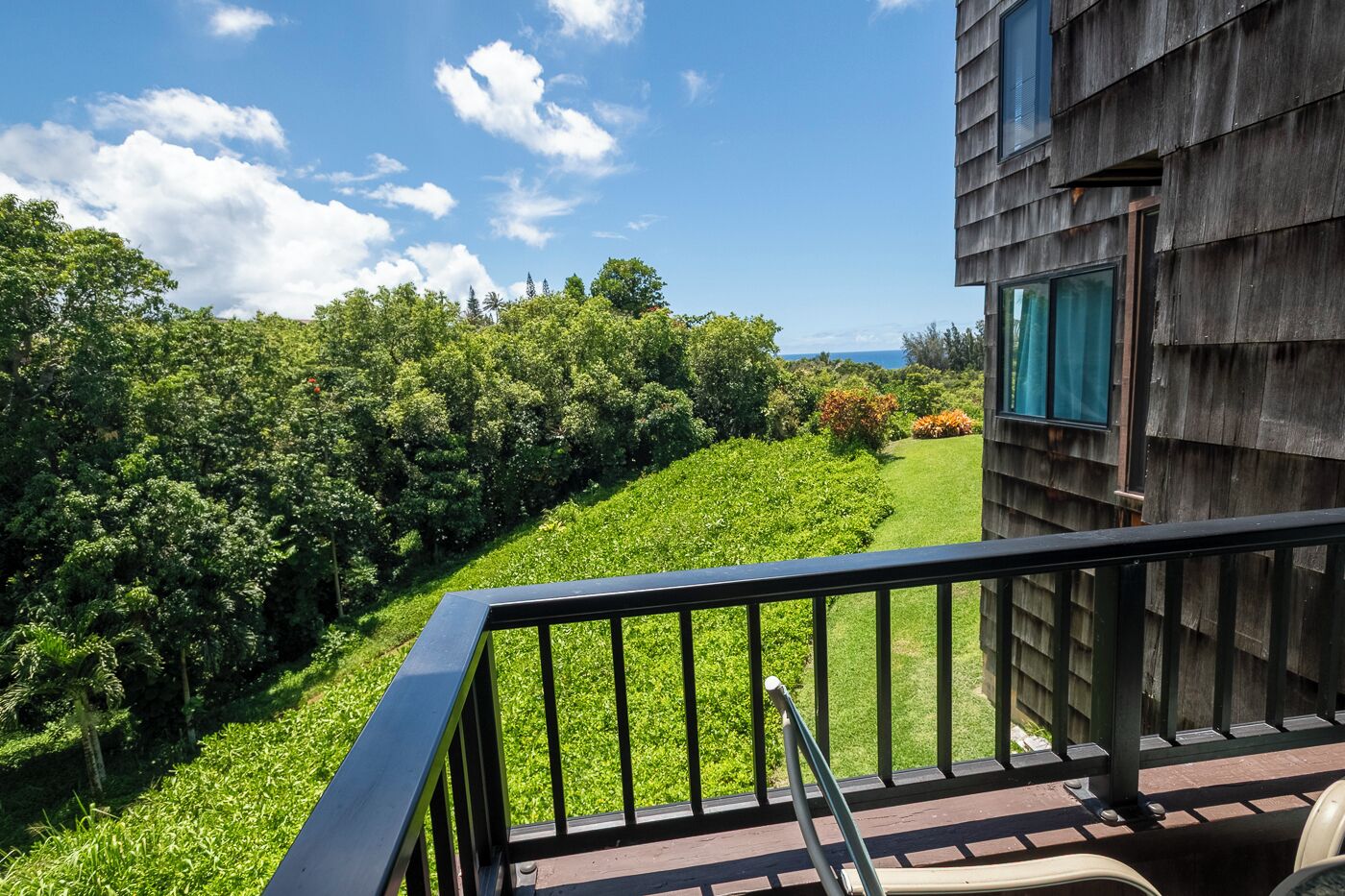 A balcony with a view of a lush garden and a wooden building.