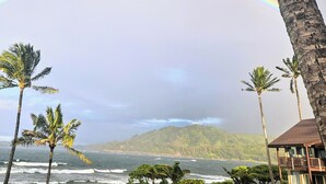 A beach with palm trees, a house with a balcony, and a mountain in the background. - Hanalei Colony Resort H4 (Hanalei)
