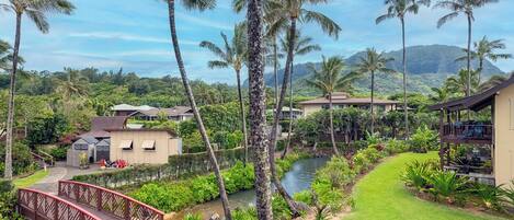 A tropical resort with a pool, palm trees, and a bridge.