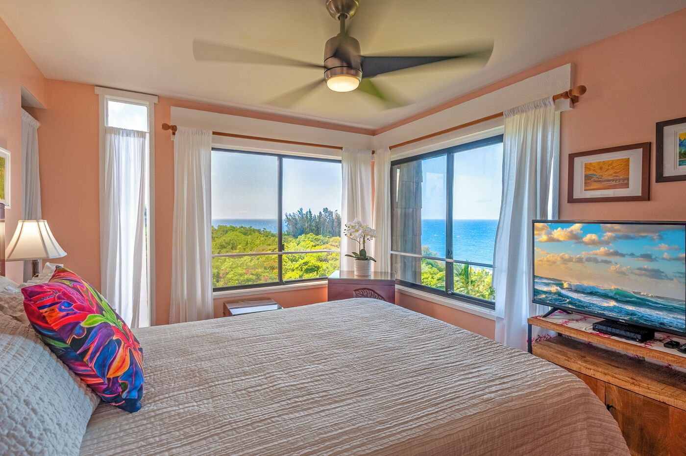 Un dormitorio con cama, televisor y vista al océano.