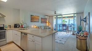 Eine moderne Küche mit einer großen Kochinsel, ein Essbereich mit Aussicht und ein Balkon mit Pool.
