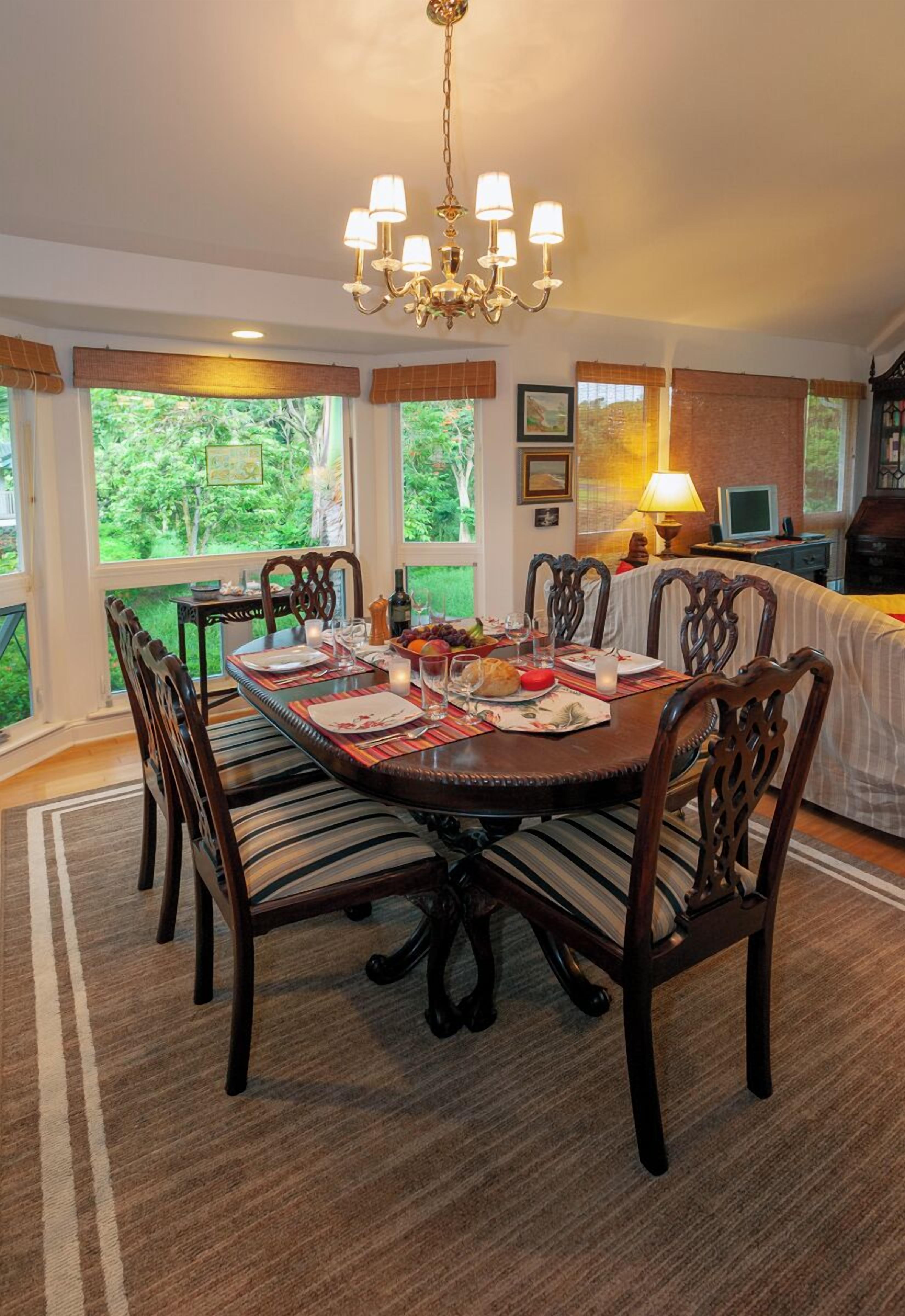 A dining room with a large wooden table, six chairs, and a chandelier.