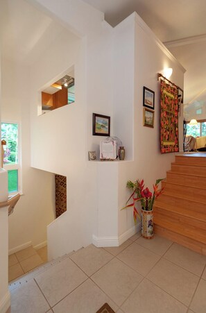 Een modern interieur met een trap, een kleine nis met een spiegel en een decoratieve vaas.