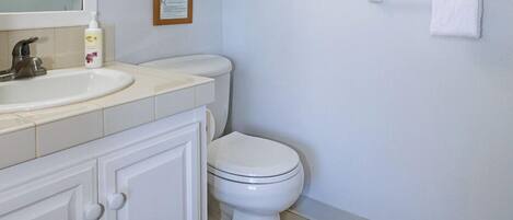 A bathroom with a toilet, sink, and mirror.