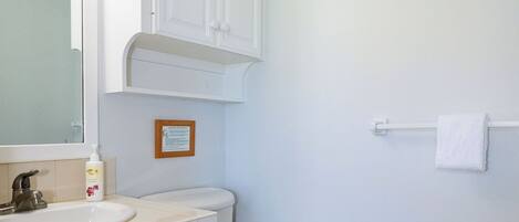 A bathroom with a white toilet, a sink with a mirror, and a towel rack.