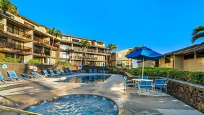 Uma área de piscina de hotel com espreguiçadeiras e uma banheira de hidromassagem.