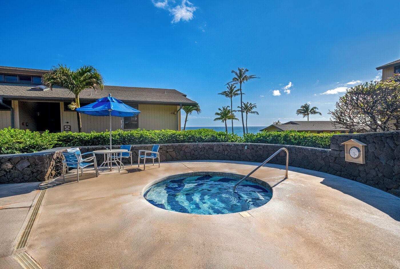 A pool area with a hot tub, lounge chairs, and a clock on the wall.