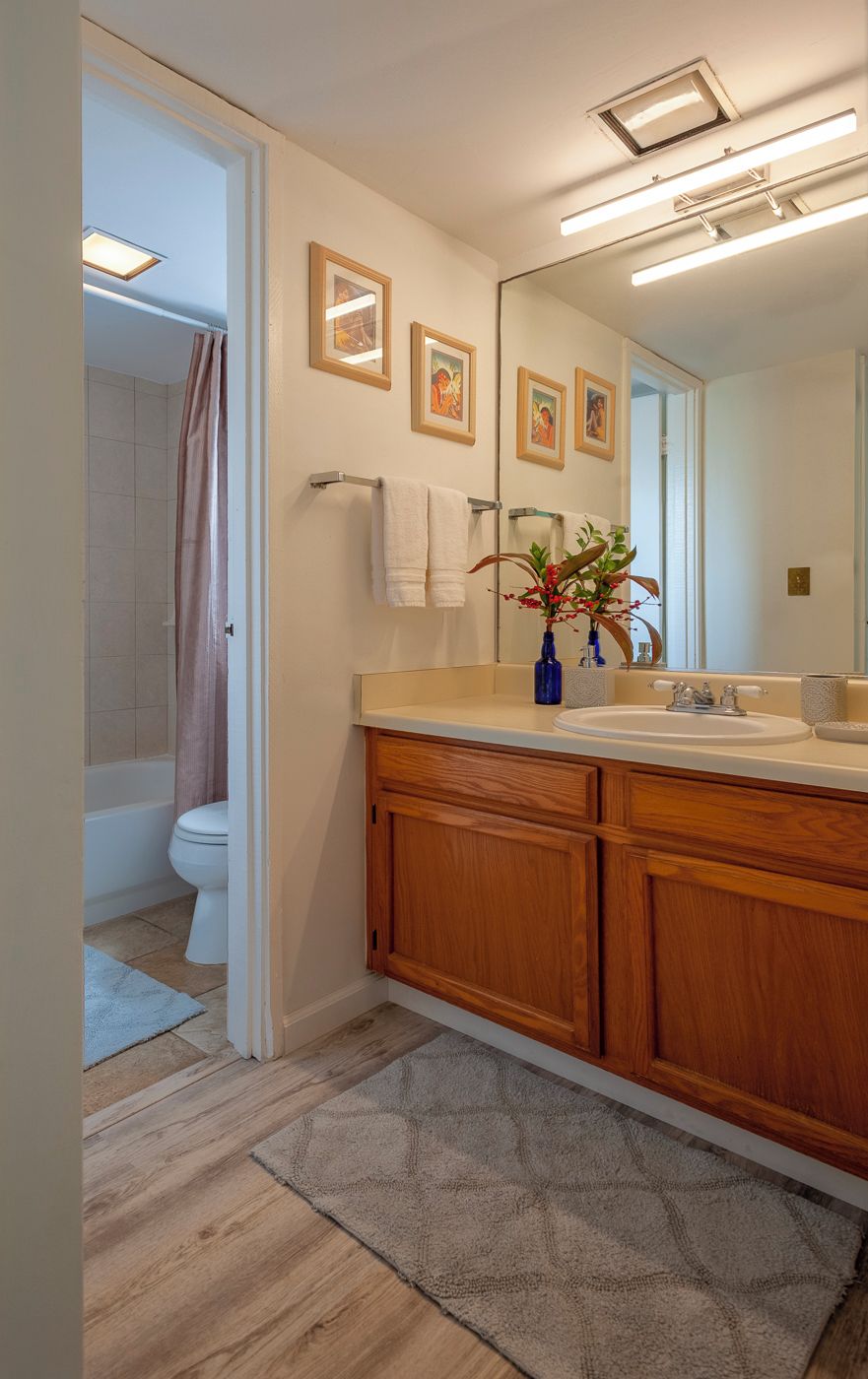 A modern bathroom with a wooden vanity, a large mirror, and a shower area.