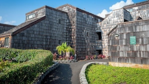 A building with a wooden exterior and a pathway leading to the entrance. - Sealodge E10 (Princeville)