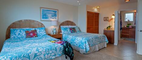 A bedroom with two beds, a ceiling fan, a nightstand with a lamp, and a framed picture on the wall.