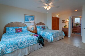 A bedroom with two beds, a ceiling fan, a nightstand with a lamp, and a framed picture on the wall. - Alii Kai 3103 (Princeville)