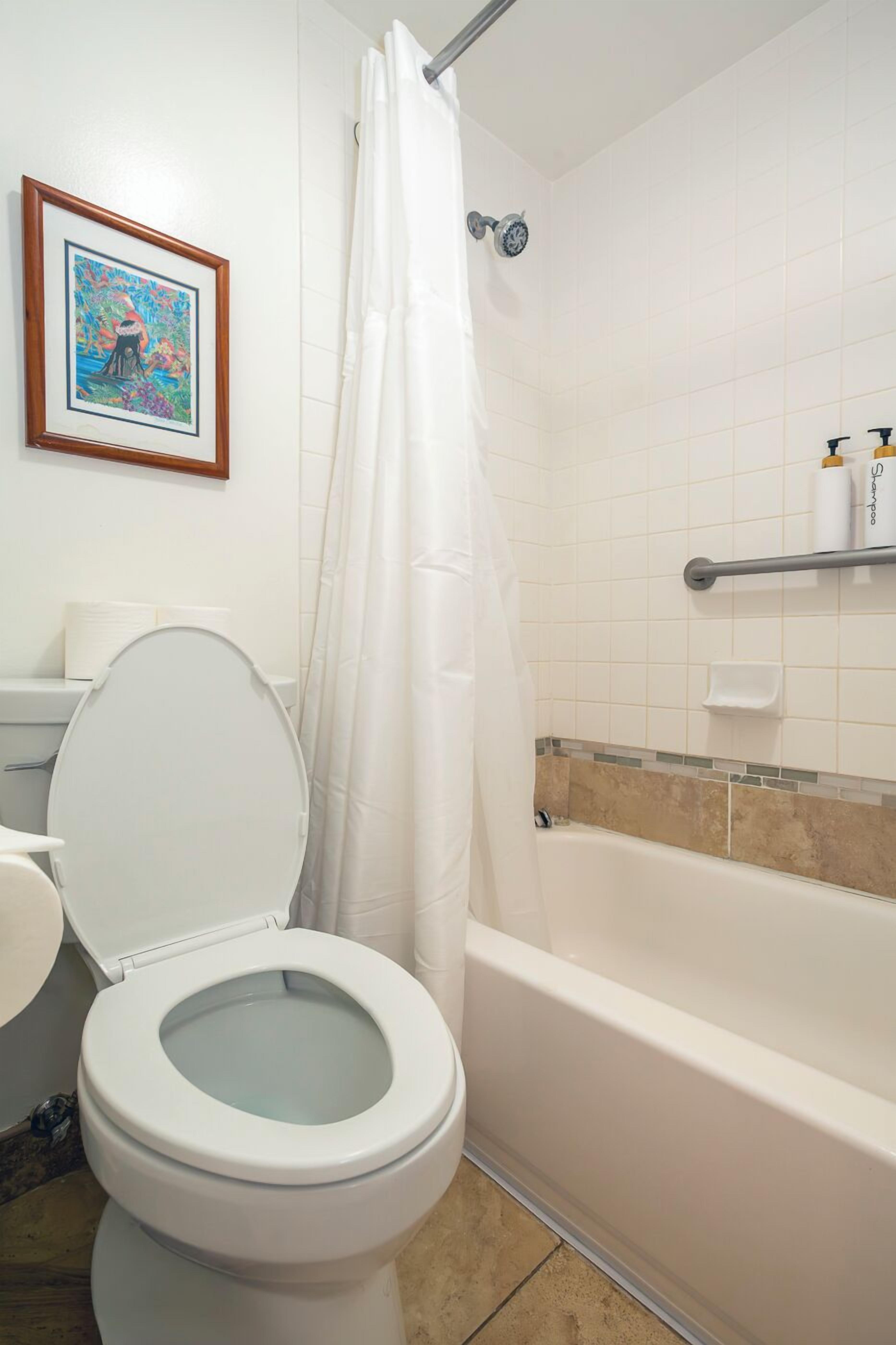 A bathroom with a toilet, a shower curtain, a bathtub, and a shelf with toiletries.