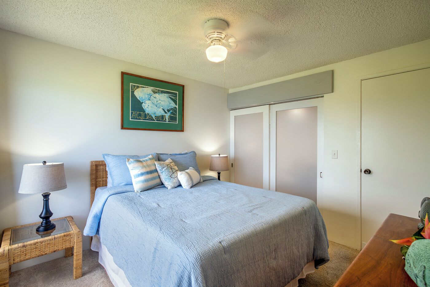 A bedroom with a bed, two bedside tables with lamps, a framed picture on the wall, and a closet.