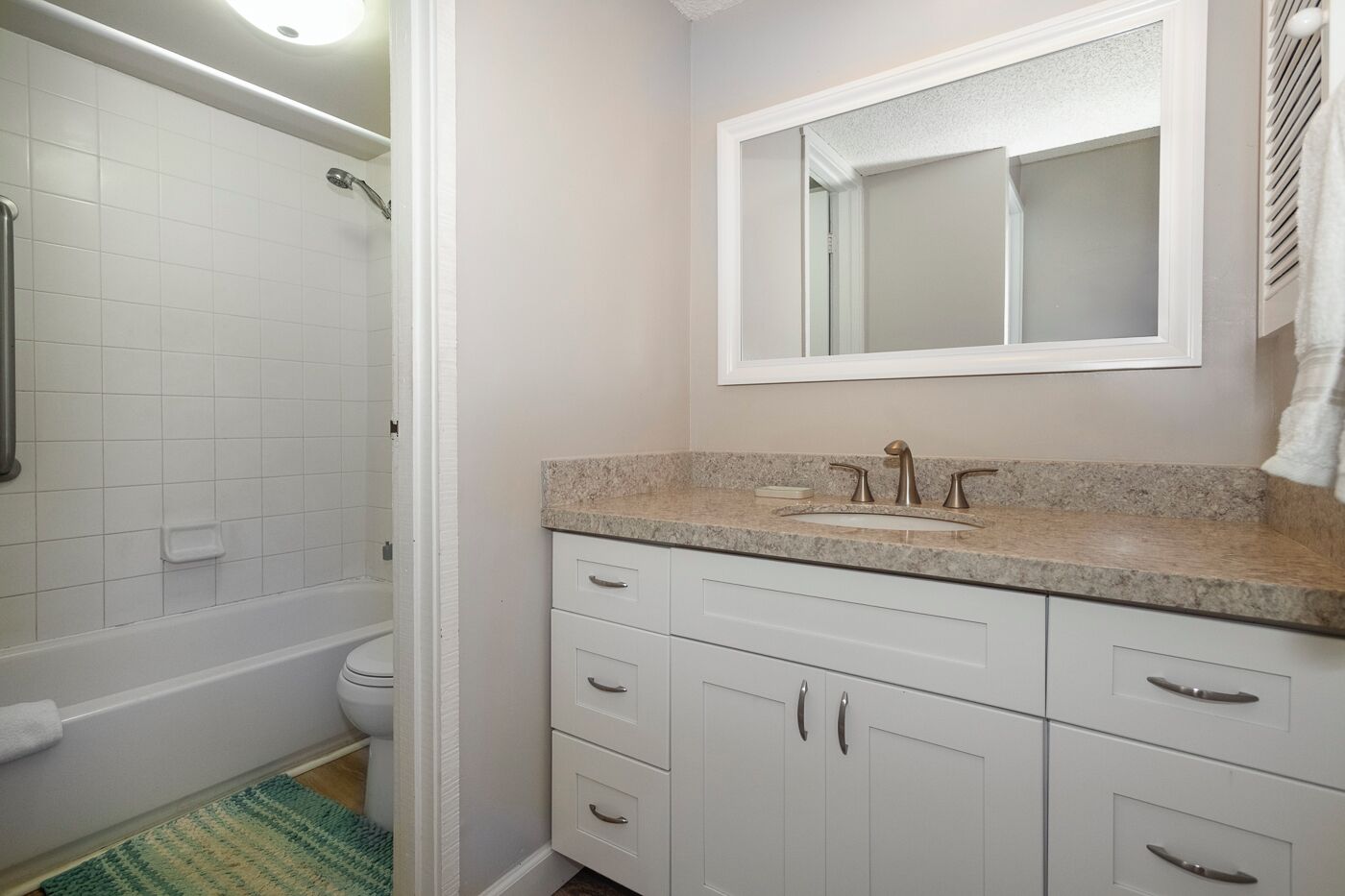 A bathroom with a shower, toilet, sink, and a mirror above the sink.