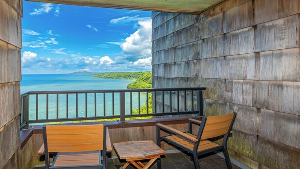 A balcony with wooden furniture and a view of the ocean. - Sealodge E8 (Princeville)