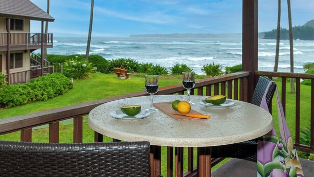 Une table ronde, un verre de vin rouge, un bol de guacamole et une demi-avocat, le tout sur un balcon donnant sur l’océan.