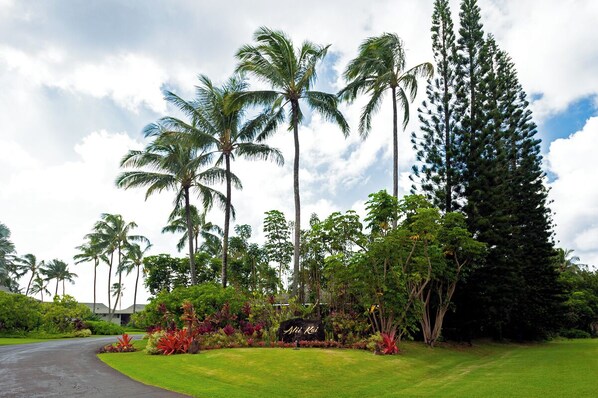 Un exuberante jardín con palmeras y un letrero que dice "Aloha Kai".