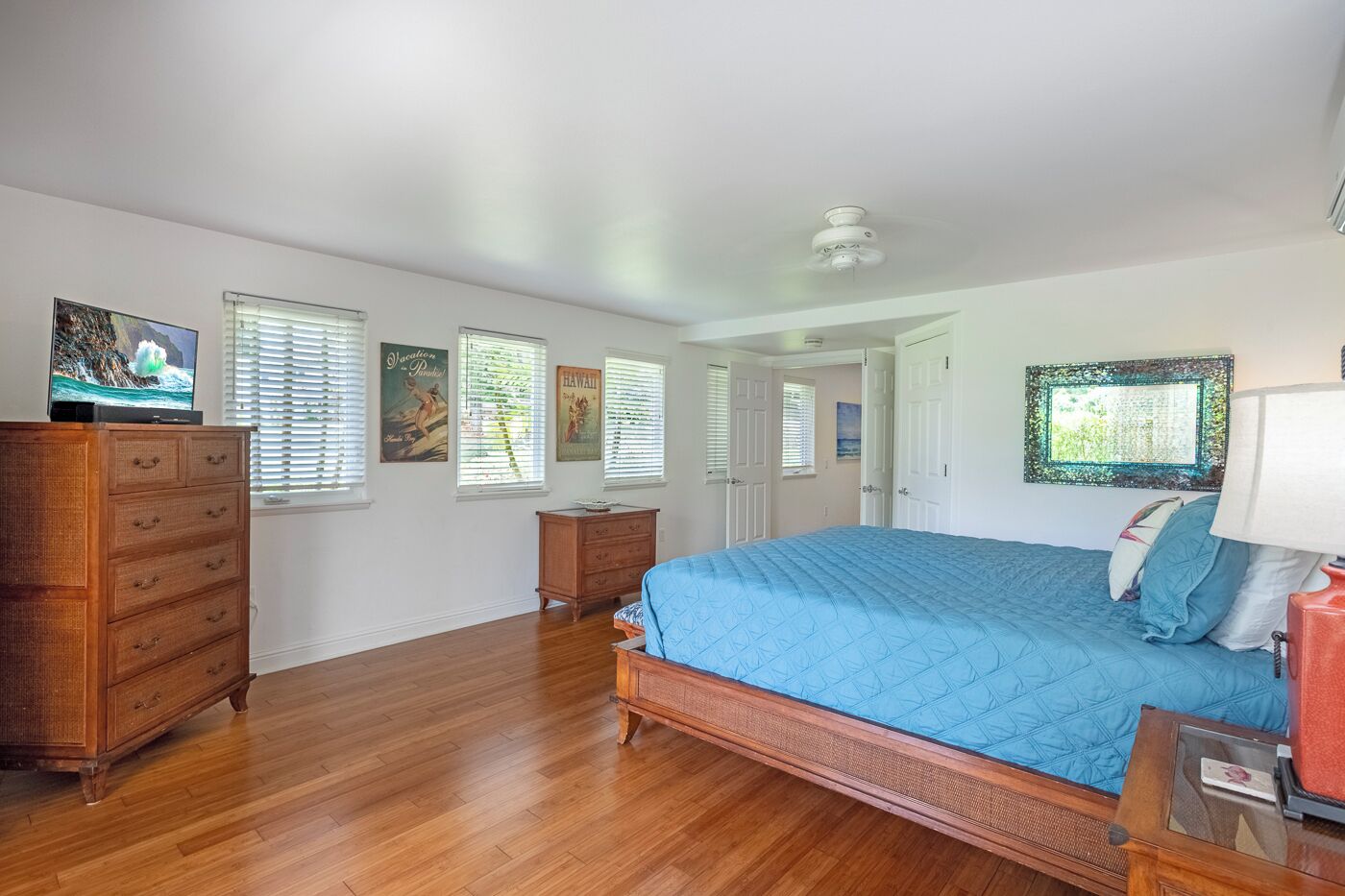 A bedroom with a bed, dresser, and a television on a stand.