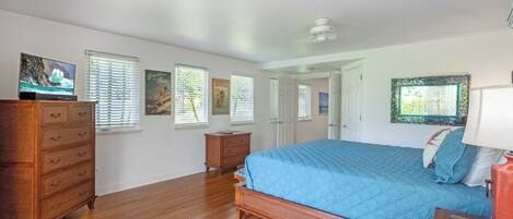 A bedroom with a bed, dresser, and a television on a stand.