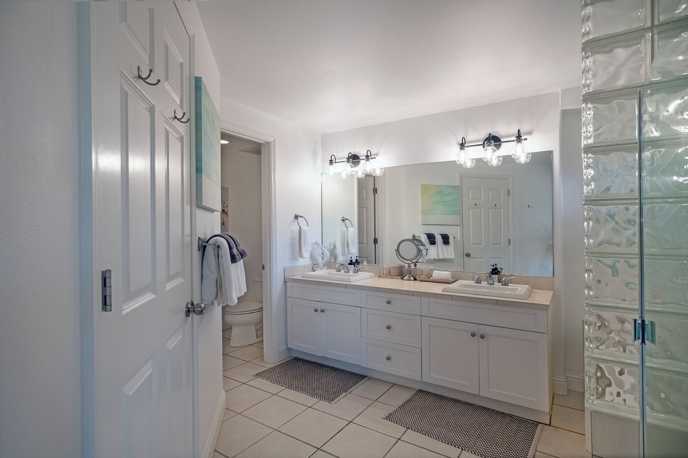 Un baño moderno con un tocador grande, dos lavamanos, un espejo y una cabina de ducha de vidrio.