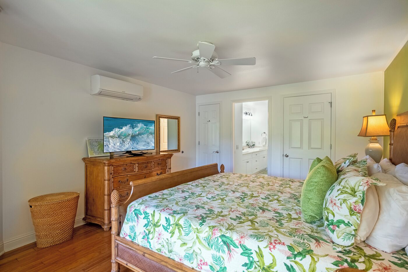 Ein Schlafzimmer mit Bett, Kommode, Fernseher, Deckenventilator und Tür.
